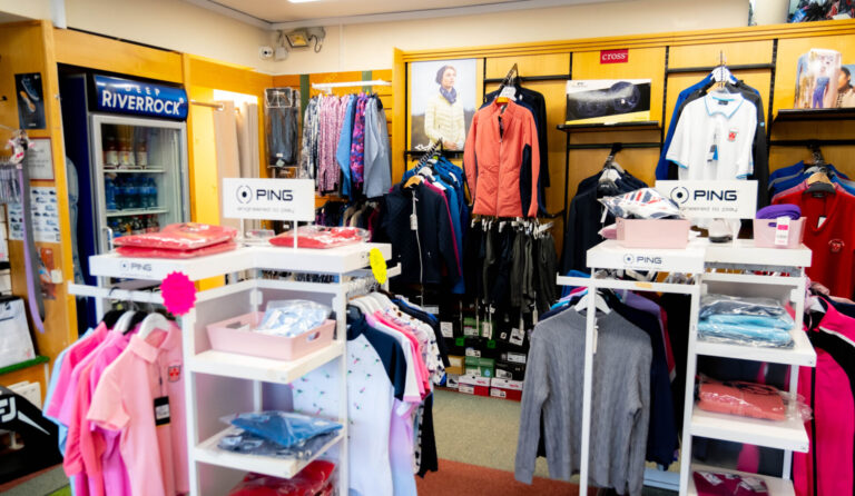 Golf apparel shop with colorful shirts, jackets, and accessories displayed on racks and shelves.