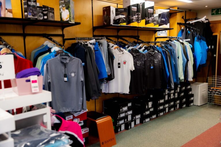 Golf apparel store interior with polos, jackets, and accessories on display.