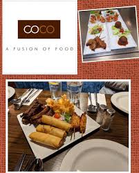 Plate of assorted fusion appetizers at COCO restaurant with a logo and menu display on textured background.