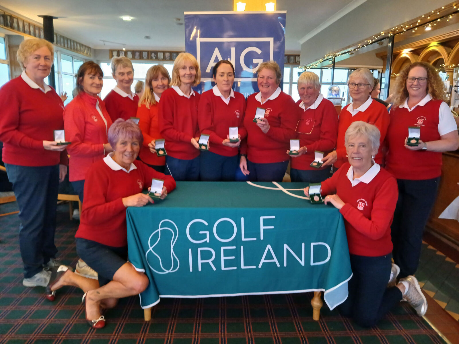 Group of women golfers in red sweaters celebrating with medals at Golf Ireland event.