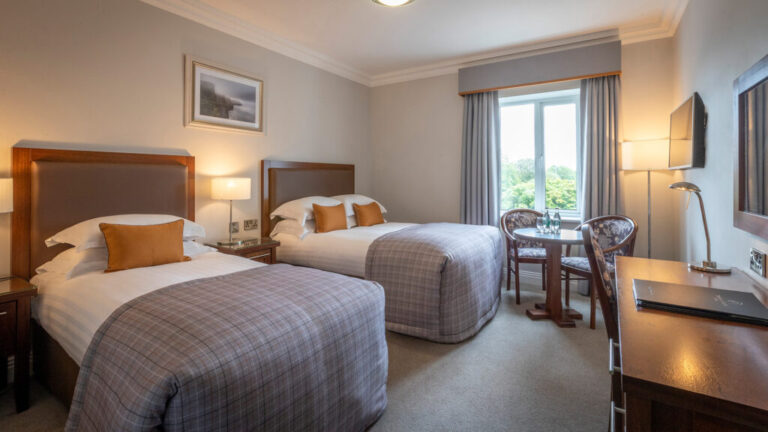 Cozy hotel room with two beds, modern decor, and a window with a scenic view. Perfect for a peaceful stay.