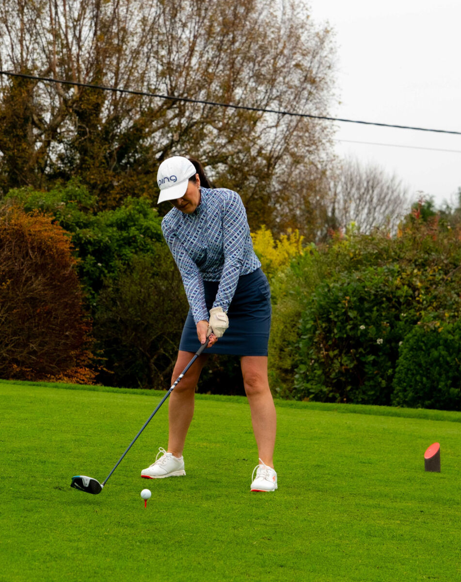Golfer in blue attire preparing to tee off on a lush green course, ready for a powerful drive.