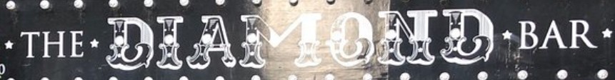 Sign reading The Diamond Bar in vintage white letters on a dark background, surrounded by decorative dots.