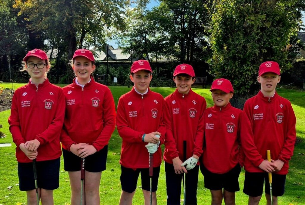 Young golf team in red uniforms posing with clubs on a sunny day in a park setting.